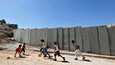 Palestiinalaislapset leikkivät lokakuussa Shuafatin pakolaisleirillä lähellä Jerusalemia. Taustalla on Israelin rakennuttama rajamuuri.