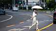 Nainen suojautui sateenvarjolla auringolta Shanghaissa.