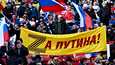 Ihmiset juhlivat Krimin Venäjään liittämisen vuosipäivää Putinin puolesta -banderollin kanssa Moskovan Lužnik-stadionilla perjantaina. 