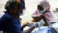 Terveydenhuollon työntekijä keskusteli Astra Zenecan koronarokotteen saaneen naisen kanssa rokotuksen jälkeen Nigerian Lagosissa marraskuussa.