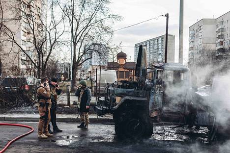 Ukrainalaiset sotilaat seisoivat palaneen ajoneuvon vieressä Kiovassa 25. helmikuuta.