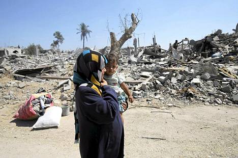 Palestiinalaisnainen käveli tyttärensä kanssa tuhoutuneiden talojen raunioissa Khuzaan kylässä Gazassa keskiviikkona.