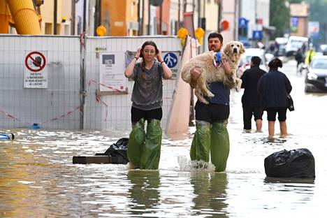 Jalankulkija kantoi koiraansa tulvineella kadulla Lugossa Italiassa torstaina.
