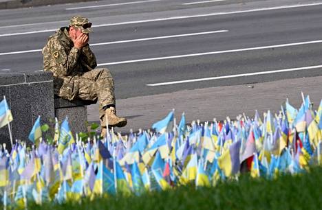 A Ukrainian soldier sat by a memorial made of miniature flags in the center of Kyiv at the end of October.  Each flag symbolizes one fallen Ukrainian soldier.