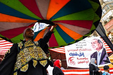 Tanssiva dervišši ja istuvan presidentin Abdel Fattah al-Sisin vaalijuliste Kairossa. Kuva on keskiviikolta, kolmipäiväisten presidentinvaalien viimeiseltä päivältä.