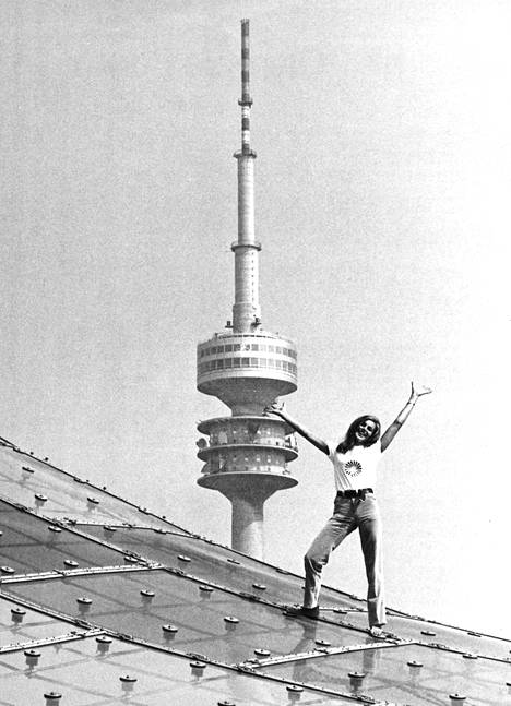 Kaksi Münchenin kisojen symboolia: 290 metriä korkea tv-masto ja 168 senttiä pitkä Miss München, Uschi Badenberg. Kuvausalustana on päästadionin muovinen katto.