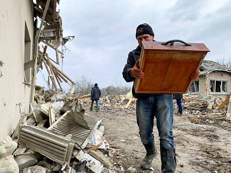 Mies kantoi pelastamiaan tavaroita raunioituneesta kodistaan Lvivin alueella torstaina.