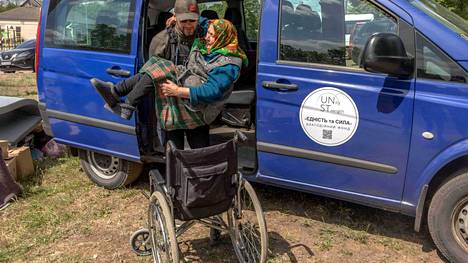 Ukrainalainen avustustyöntekijä auttoi Vovtšanskista evakuoitua ukrainalaista eläkeläistä Harkovan evakuointikeskuksessa sunnuntaina 12. toukokuuta.