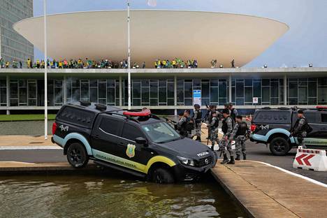 Liittovaltion kongressin poliisijoukot ihmettelivät altaaseen jumittunutta autoaan Jair Bolsonaron kannattajien kiivettyä kongressitalon katolle Brasíliassa sunnuntaina.