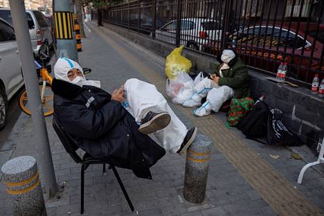 Vartijat istuivat rennosti koronan vuoksi suljetun asuinalueen edessä Pekingissä keskiviikkona.