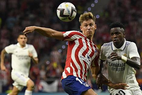 Atléticon Marcos Llorente (vas.) yrittii pysäyttää Real Madridin brassihyökkääjän Vinicius Juniorin Madridin paikalliskohtaamisessa.
