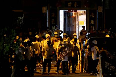 Valkopaitaisia miehiä pamppuineen ja keppeineen nähtiin rautieasemalla tapahtuneen hyökkäyksen jälkeen 22. heinäkuuta Hongkongissa.
