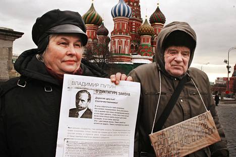 Venäjän presidentinvaaleissa opposition mielenilmaukset ovat olleet lähes huomaamattomia. Kuvassa kaksi kansalaista Punaisen torin laidalla. Naisen paperissa (Putinin kuva) ehdotetaan diktatuurin lakkoa.