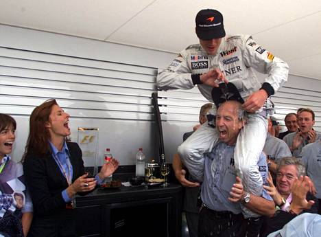 Mika Häkkinen remusi Nürburgringillä voiton jälkeen vuonna 1998. Hän kaatoi kuohujuomaa johtaja Jo Ramirezin päälle. Erja Häkkinen nauroi vieressä.