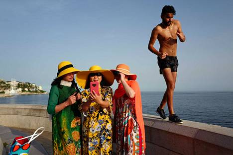 Mies lenkkeili selfieitä ottavien turistien ohi Ranskan Nizzassa maanantaina. Ranskaan on luvattu kuluvalla viikolla jopa 40 lämpöastetta.