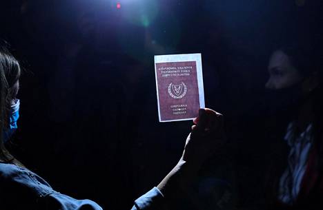 Mielenosoittaja pitelee kuvaa Kyproksen passista korruption vastaisessa mielenosoituksessa 14. lokakuuta maan pääkaupungissa Nikosiassa. Mielenosoituksessa vastustettiin muun muassa passien myymistä ulkomaalaisille.