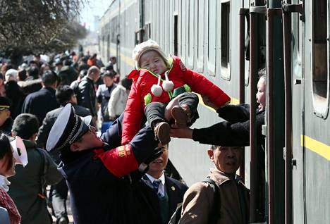 Poliisi auttaa lasta pääsemään junaan Yunchengissa Kiinassa helmikuussa 2018.