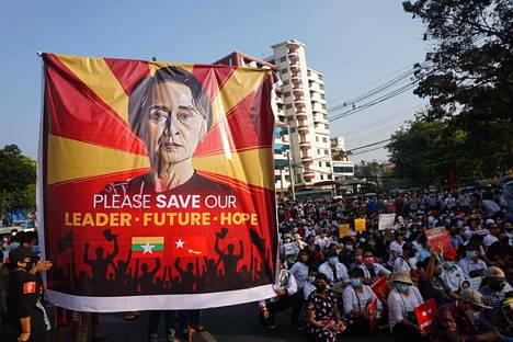 Myanmarin sotilasjunttaa vastustavat mielenosoittajat pitelivät Aung San Suu Kyitä esittävää banderollia Yangonissa NLD:n puoluetoimiston luona vuonna 2021.
