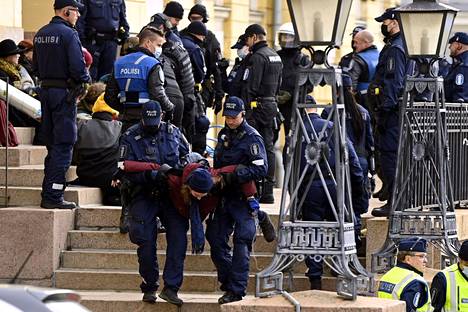 Poliisit siirsivät mielenosoittajia pois Valtioneuvoston linnan edustalta perjantaina.