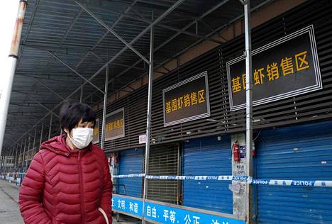 Kasvomaskilla suojautunut nainen käveli Wuhanin suljetun kalatorin ohitse 12. tammikuuta.