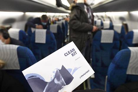 Lentomatkustajia Finnairin koneessa Helsinki-Vantaan lentokentällä 26. marraskuuta. Kuvan Clean Kit on tarkoitettu käsien ja pintojen desinfiointiin.