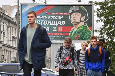 Young men walked past an army recruitment advertisement in St. Petersburg on Thursday.  Serving Russia is real work, the advertisement reads.