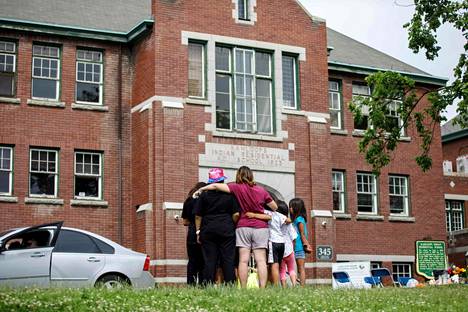 Perhe katseli entisen alkuperäiskansojen lasten sisäoppilaitoksen rakennusta Brittiläisessä Kolumbiassa Kanadassa kesäkuussa. Tuolloin koulun alueelta oli löytynyt 215 lapsen haudatut jäännökset.