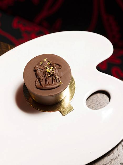 Taiteilija Riikka Purosen suunnitteleman suklaa-mantelikakun päälle on ripoteltu lehtikultaa. Leivos päättää aterian ylellisesti.