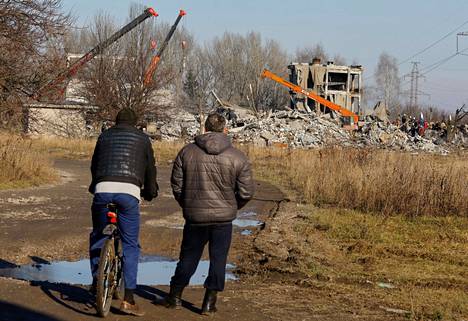 Miehiä seuraamassa raivaustöitä. Rakennus, jossa Venäjä oli majoittanut joukkojaan, tuhoutui Ukrainan iskussa täysin.