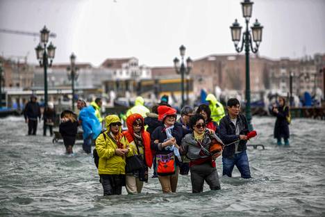 Turistit kulkivat tulvaveden valtaamalla Pyhän Markuksen aukiolla Venetsiassa maanantaina.