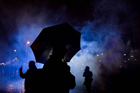 Mies piteli mielenosoituksen aikana Pariisissa sateenvarjoa, joka suojaa poliisin vesitykeiltä.