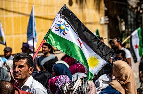 Mies piteli Qamishlin kaupungissa syyskuussa Syyrian vanhaa lippua, jonka kolmesta tähdestä reunimmaiset oli korvattu assyrialaisten tunnuksella (vas.) ja kurdien aurinkosymbolilla.