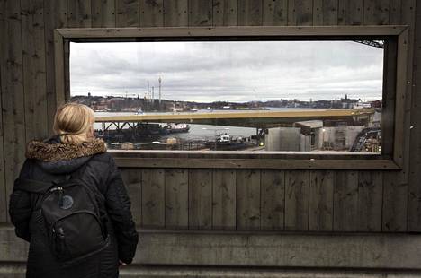Nainen katseli kävelytien kurkistusaukosta, kun Slussenin uutta siltaa kuljetettiin paikoilleen perjantaina. Koronavirusepidemian etenemisen vuoksi katselijat olivat paljon harvemmassa kuin runsasta viikkoa aiemmin sillan saapuessa.