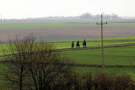 Poliiseja käveli Przewodówin kylän pelloilla lähellä paikkaa, johon osui tiistaina Ukrainan ilmatorjuntaohjus.