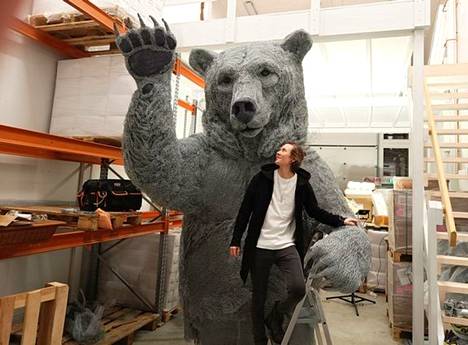  Taiteilija Eliya Zweygberg Urho-karhun kainalossa ateljeellaan. Urhon korkeus on 3 metriä (jalustan kanssa 3,3 m), leveys 180 senttimetriä ja paino noin 600 kiloa. Teräsverkkoa veistoksessa noin 1 500 metriä ja rautalankaa tuhansia metrejä – taiteilijakaan ei ole pysynyt laskuissa mukana. 