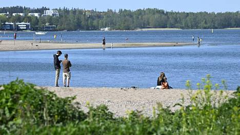 Ulkoilijat nauttivat aurinkoisesta ja lämpimästä säästä Hietaniemen rannalla Helsingissä sunnuntaina.