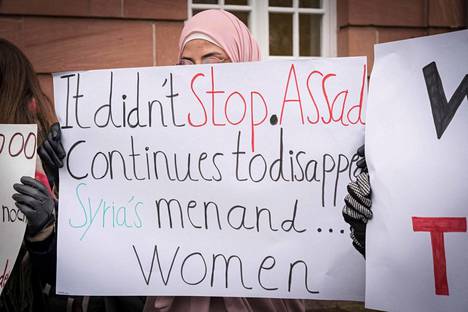 Mielenosoittajia Anwar Raslanin tuomiosta päättäneen oikeustalon ulkopuolella Koblenzissa torstaina. Kyltissä sanotaan, että naisia ja miehiä katoaa yhä Syyrian diktaattorin Bašar al-Assadin vallan alaisuudessa.