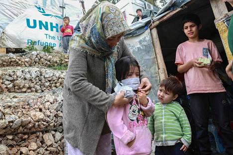 Nainen laittaa hengityssuojan lapselle Morian pakolaisleirillä.