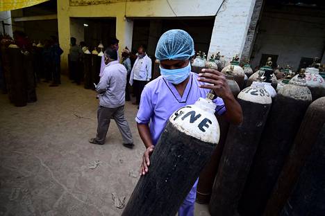 Terveydenhuollon työntekijä kantoi koronaviruspotilaille tarkoitettua varahappisylinteriä täyttöpisteellä Allahabadissa Intiassa tiistaina.