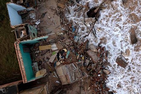 Mies keräili pelastettavissa olevia tavaroita ja materiaaleja merenpinnan alle jääneen talon raunioista Atafonassa helmikuun alussa. 