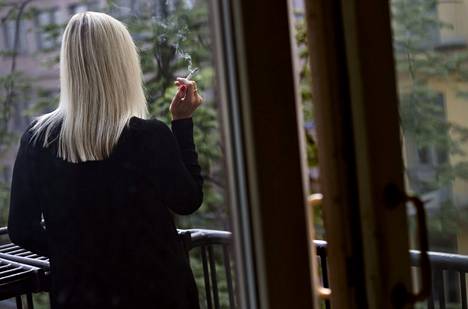 Tupakointi asunnoissa voi aiheuttaa terveyshaitan lisäksi omaisuus­vahinkoja ja laskea asunnon arvoa. Nainen tupakoi parvekkeella Helsingissä 7. elokuuta 2018.