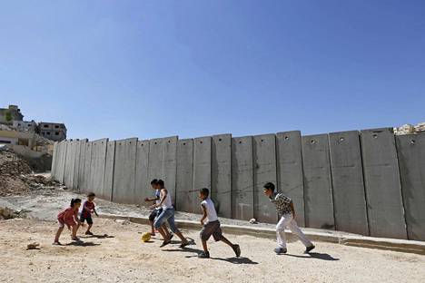 Palestiinalaislapset leikkivät Israelin rakentaman muurin vieressä Shuafatissa Länsirannalla lähellä Jerusalemia.