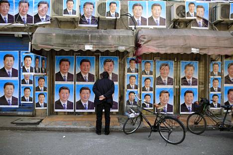 Kiinalaismies tutki keskiviikkona seinää, joka on tapetoitu presidentti Xi Jinpingin kuvilla.