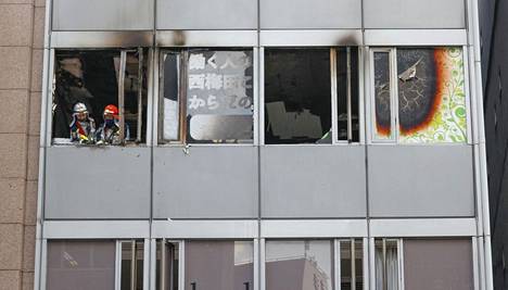 Palomiehiä Osakassa palaneen talon ikkunan luona.