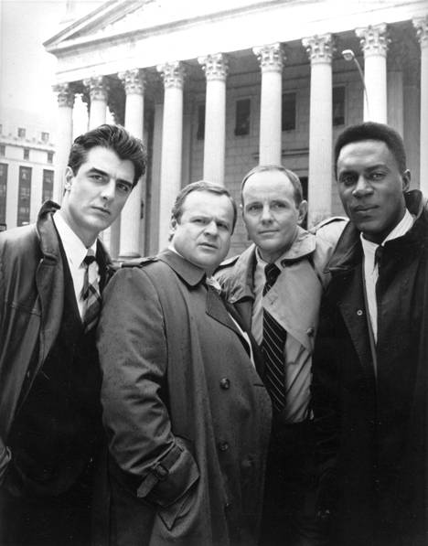 Kova laki -sarjan ensimmäisiä poliiseja esittivät Chris Noth (vas.) ja George Dzundza ja apulaissyyttäjiä Michael Moriarty ja Richard Brooks.