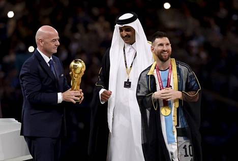 Fifan puheenjohtaja Gianni Infantino (vas.) ja Qatarin emiiri Tamim bin Hamad al-Thani palkitsevat Lionel Messin sunnuntaina jalkapallon MM-finaalin jälkeen. Messin yllä on arabikulttuuriin kuuluva juhlallinen kaapua. 