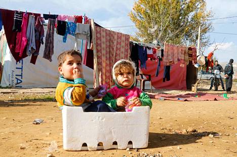 Syyrialaiset pakolaislapset istuivat laatikossa tilapäisellä leirillä Bekaan laaksossa Libanonissa maanantaina.