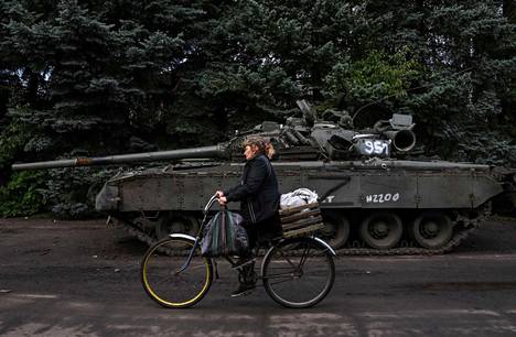 Paikallinen nainen pyöräili Venäjän armeijan hylkäämän T-80-panssarivaunun ohi Itä-Ukrainan Kramatorskissa 29. syyskuuta.