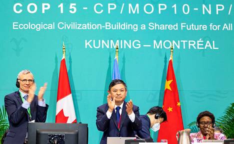 Kiinan ympäristöministeri Huang Runqiu (keskellä) taputti YK:n luontokokouksessa keskellä yötä saavutetun historiallisen sovun varmistuttua. Kiina oli kokouksen puheenjohtaja.