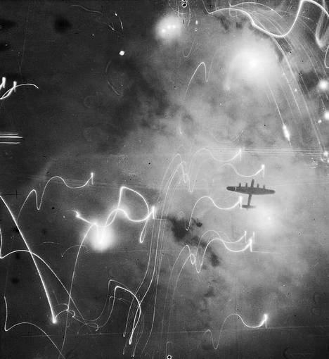 Lancaster-pommikone Hampurin yllä 31.1.1943 vastaisena yönä kuvattuna toisen pommikoneen kohdekameralla. Tältä näyttivät Britannian pommitusilmavoimien kaiken aikaa rajummiksi muuttuneet ilmahyökkäykset eri kohteisiin Euroopan mantereella. Suuremmat, sumeat valot ovat valoammuksia, kiemurtelevat viivat ilmatorjunnan valojuova-ammuksia. Niiden vanat kuvassa johtuvat kameran pitkästä valotusajasta ja lentokoneen liikkeistä. – Peter Englundin kirjan kuvitusta.